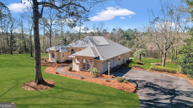 exterior space featuring roof with shingles, stucco siding, a garage, a yard, and driveway