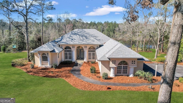 view of front facade with a front lawn, french doors, a forest view, and stucco siding