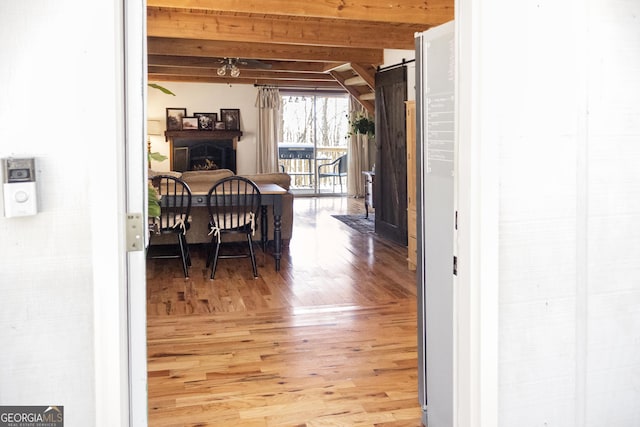 interior space featuring beam ceiling, light wood-style flooring, and a barn door