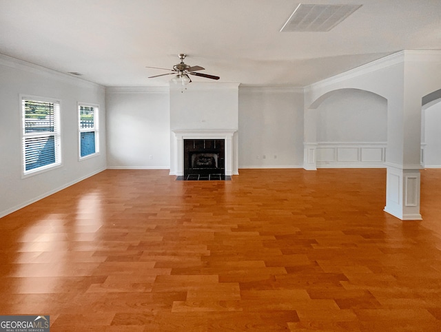 unfurnished living room with visible vents, crown molding, light wood-style flooring, a fireplace, and a ceiling fan