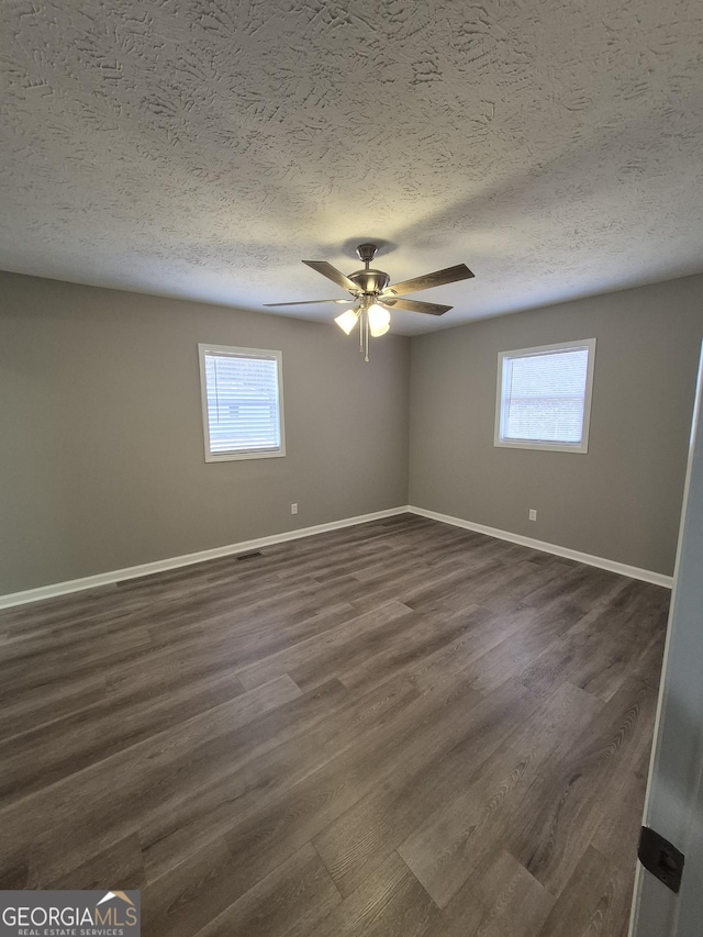 spare room with visible vents, baseboards, a textured ceiling, a ceiling fan, and dark wood-style flooring