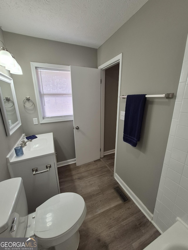 full bathroom featuring wood finished floors, baseboards, visible vents, a textured ceiling, and toilet