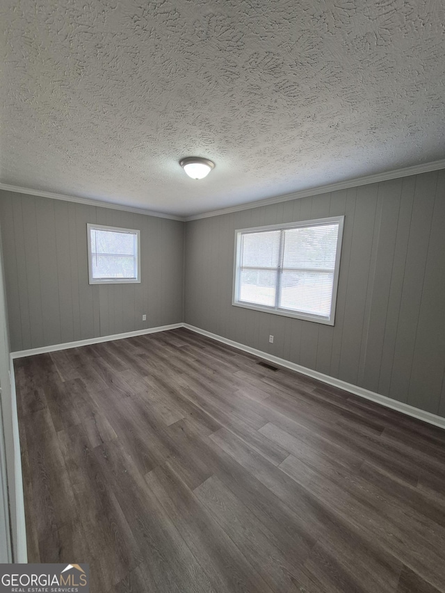 unfurnished room with dark wood finished floors, visible vents, crown molding, and baseboards