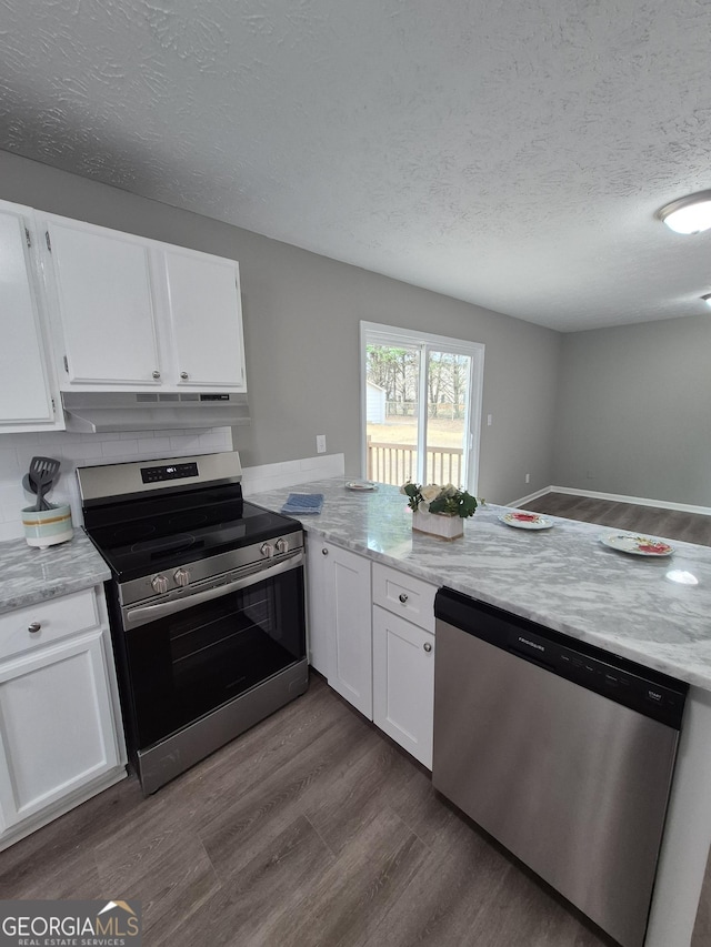 kitchen with under cabinet range hood, a textured ceiling, dark wood-style floors, stainless steel appliances, and white cabinets