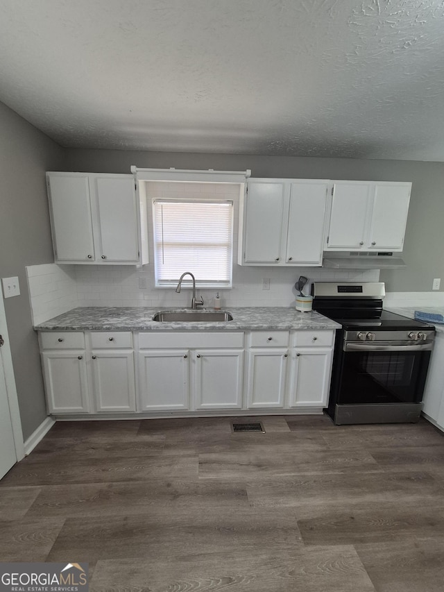 kitchen featuring dark wood-style floors, visible vents, stainless steel electric stove, a sink, and white cabinets