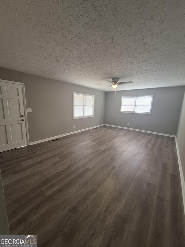 empty room with dark wood finished floors, baseboards, and ceiling fan