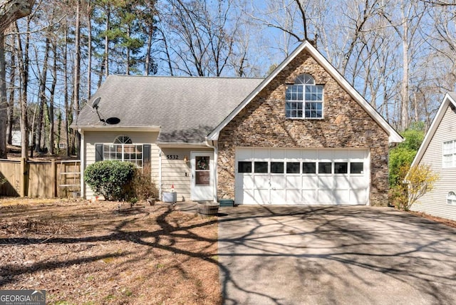 view of front of home featuring fence, concrete driveway, roof with shingles, stone siding, and an attached garage