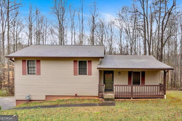 split level home with a porch, a front lawn, and a shingled roof