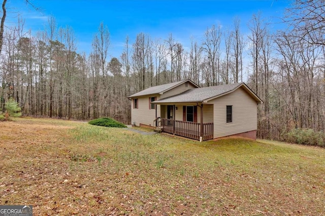 view of side of home with a porch, a view of trees, and a lawn