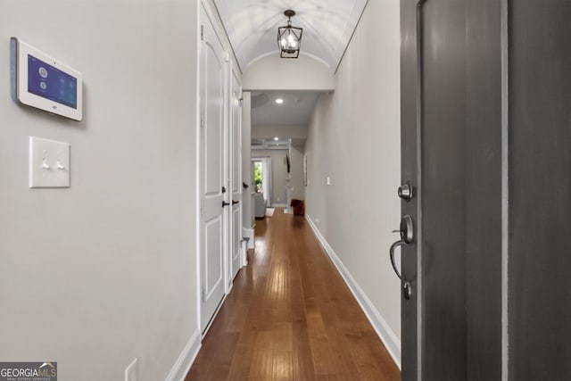 hallway with vaulted ceiling, dark wood-style floors, and baseboards