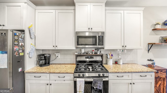 kitchen featuring light stone counters, decorative backsplash, appliances with stainless steel finishes, white cabinetry, and open shelves