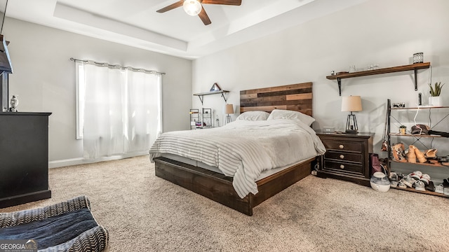 carpeted bedroom featuring baseboards, a raised ceiling, and a ceiling fan