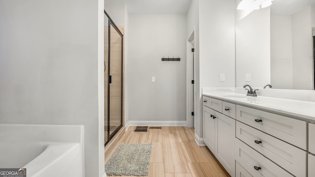 full bathroom with a stall shower, baseboards, a bath, and vanity