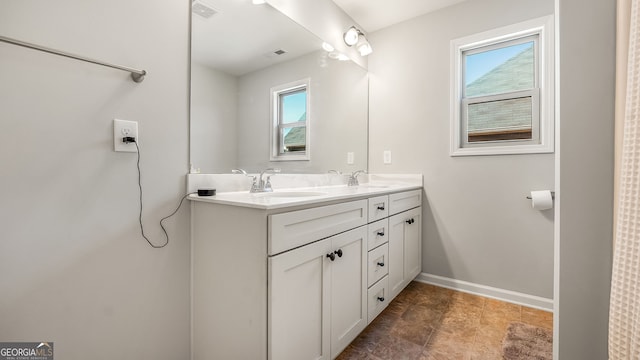 bathroom featuring double vanity, baseboards, visible vents, and a sink