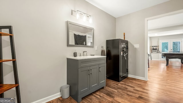 bathroom featuring french doors, vanity, baseboards, and wood finished floors