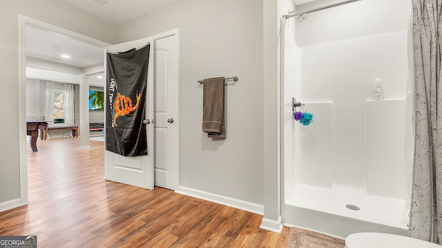 full bath featuring a shower stall, baseboards, and wood finished floors