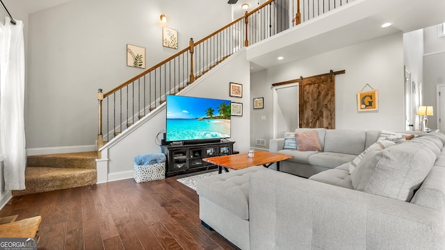 living room with stairway, wood finished floors, baseboards, a high ceiling, and a barn door