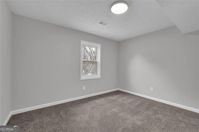 empty room featuring baseboards, visible vents, dark colored carpet, and a textured ceiling