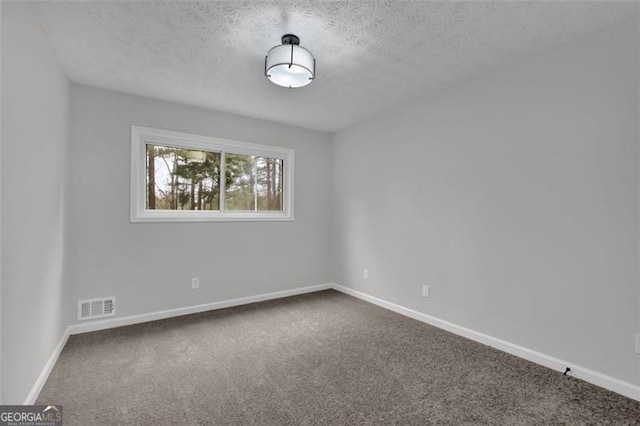 carpeted spare room featuring visible vents, baseboards, and a textured ceiling