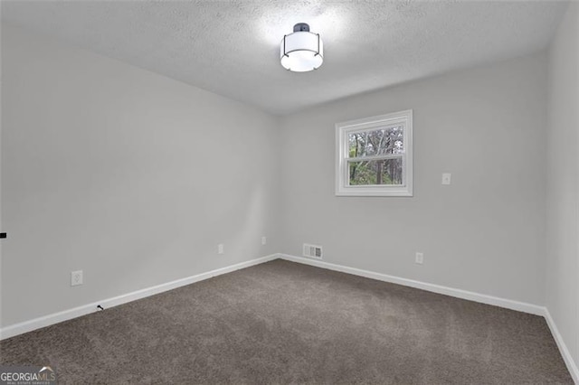 empty room featuring dark colored carpet, visible vents, baseboards, and a textured ceiling