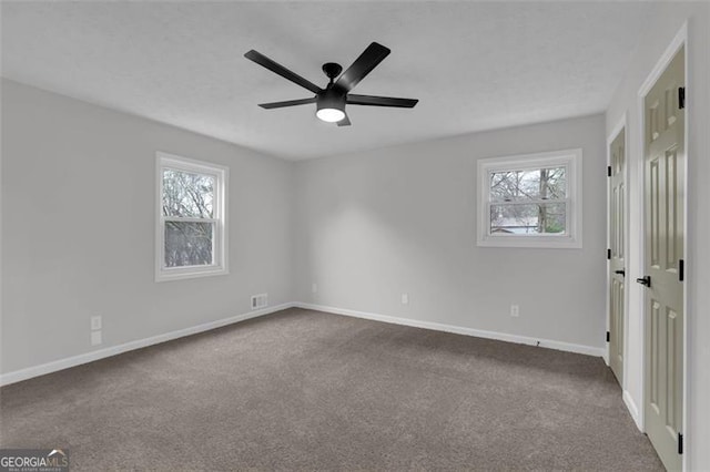 unfurnished bedroom with dark colored carpet, baseboards, and multiple windows