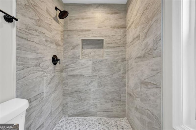 full bath featuring toilet and a tile shower