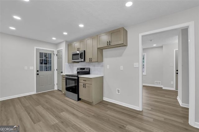 kitchen featuring baseboards, appliances with stainless steel finishes, and light wood finished floors