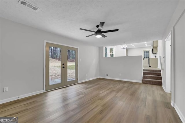 unfurnished living room with wood finished floors, french doors, visible vents, and baseboards