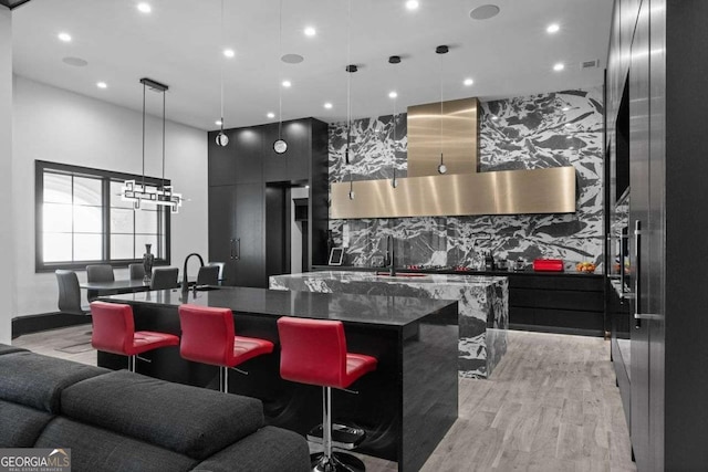 kitchen with a large island, modern cabinets, light wood-style floors, and a sink