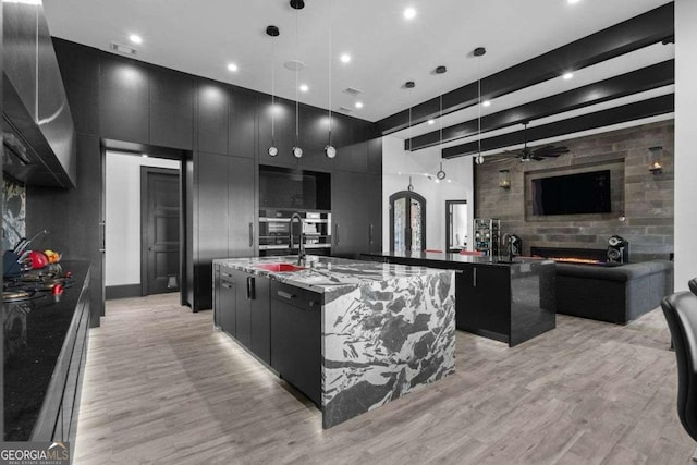 kitchen with open floor plan, a large island with sink, modern cabinets, and dark cabinetry