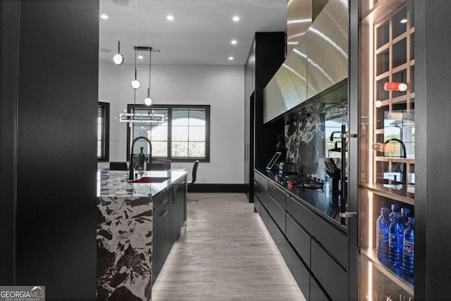 kitchen with a sink, stone counters, modern cabinets, and dark cabinets