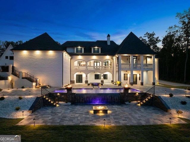 back of house featuring stairway, a balcony, a patio area, and an outdoor fire pit