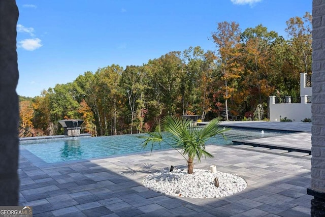 view of swimming pool featuring a patio and an infinity pool