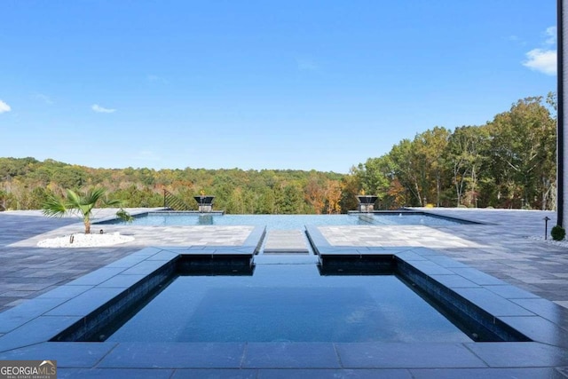 view of pool featuring a floating dock and a view of trees