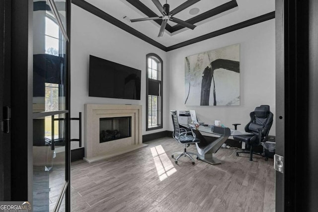 office area with a ceiling fan, a wealth of natural light, wood finished floors, and a high end fireplace