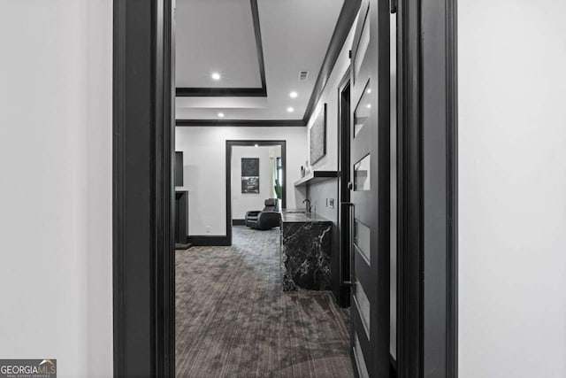 corridor featuring visible vents, ornamental molding, recessed lighting, dark colored carpet, and baseboards