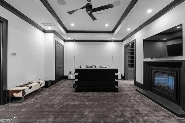 interior space with visible vents, crown molding, built in features, a glass covered fireplace, and a ceiling fan