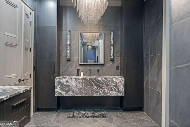 bathroom featuring vanity, an inviting chandelier, and tile walls