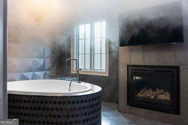 full bathroom featuring tile patterned floors, a glass covered fireplace, tile walls, and a garden tub