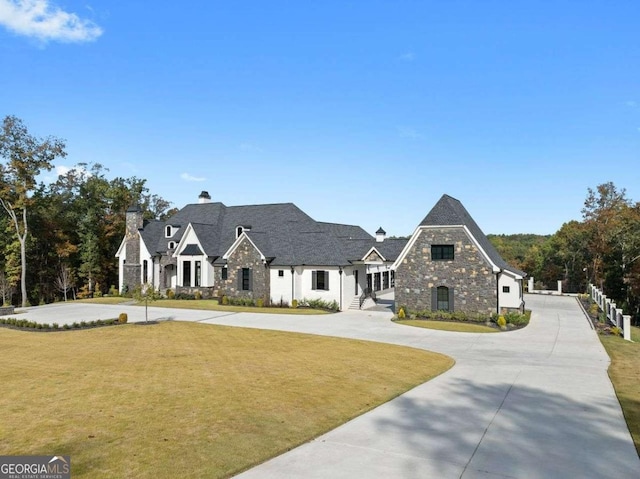 view of front of home featuring a front lawn, stone siding, and curved driveway