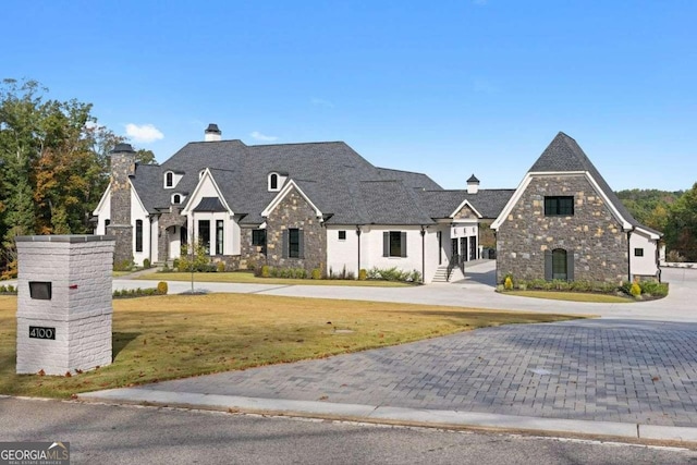 view of front of property with stone siding, a chimney, and a front yard