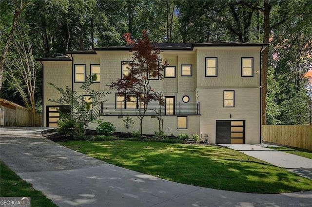 view of front of home featuring concrete driveway, fence, a garage, and a front lawn