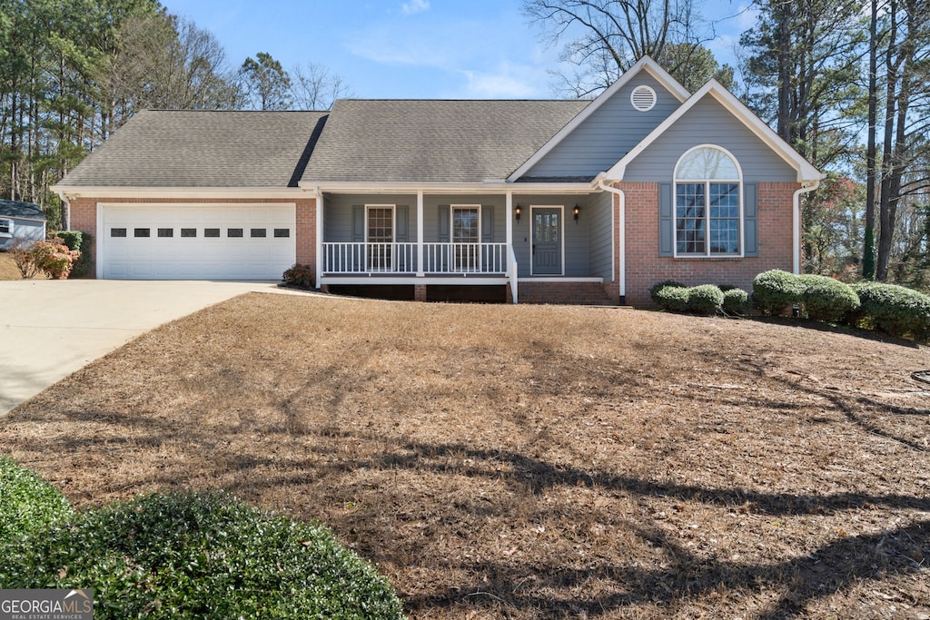 single story home with a porch, an attached garage, brick siding, and driveway