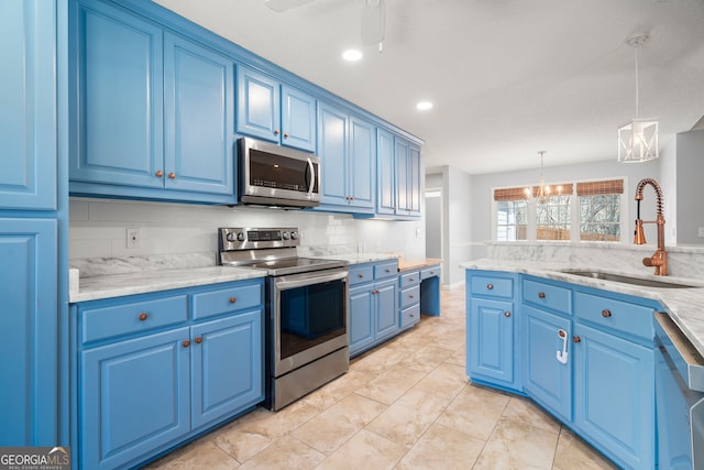 kitchen with tasteful backsplash, blue cabinetry, appliances with stainless steel finishes, hanging light fixtures, and a sink