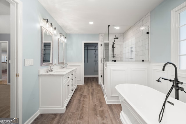 bathroom with a freestanding tub, wood finished floors, a stall shower, and a sink