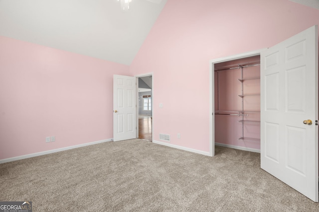 unfurnished bedroom with visible vents, high vaulted ceiling, a closet, carpet flooring, and baseboards