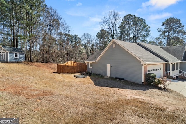 view of home's exterior featuring a storage unit, driveway, an outdoor structure, and an attached garage