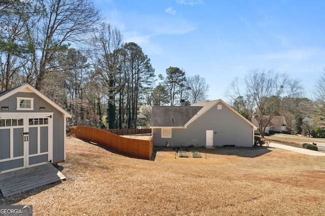 view of side of property with an outbuilding, a storage shed, and fence