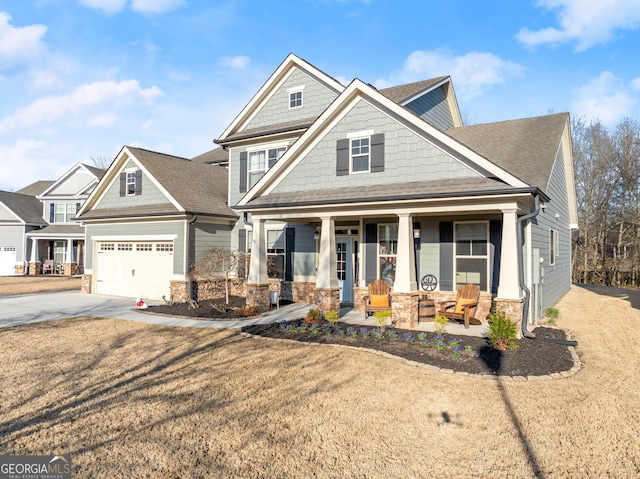 view of front facade with roof with shingles, a porch, an attached garage, concrete driveway, and stone siding