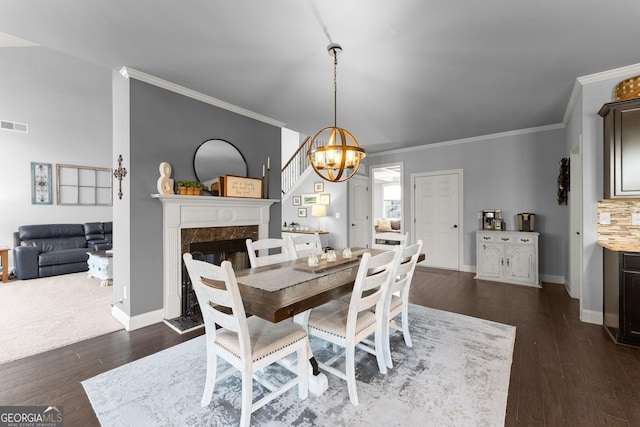 dining space featuring dark wood finished floors, a high end fireplace, an inviting chandelier, crown molding, and baseboards